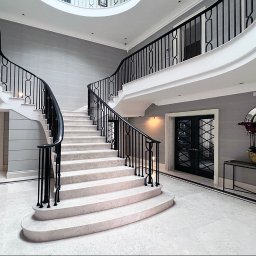 Schody betonowe obkładane kamieniem, balustrada tralkowa oraz poręcz z orzecha Amerykańskiego 