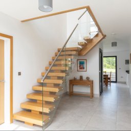 Schody dębowe na policzku centralnym z szybami oraz poręczą ze stali nierdzewnej 