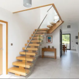 Schody dębowe na policzku centralnym z szybami oraz poręczą ze stali nierdzewnej