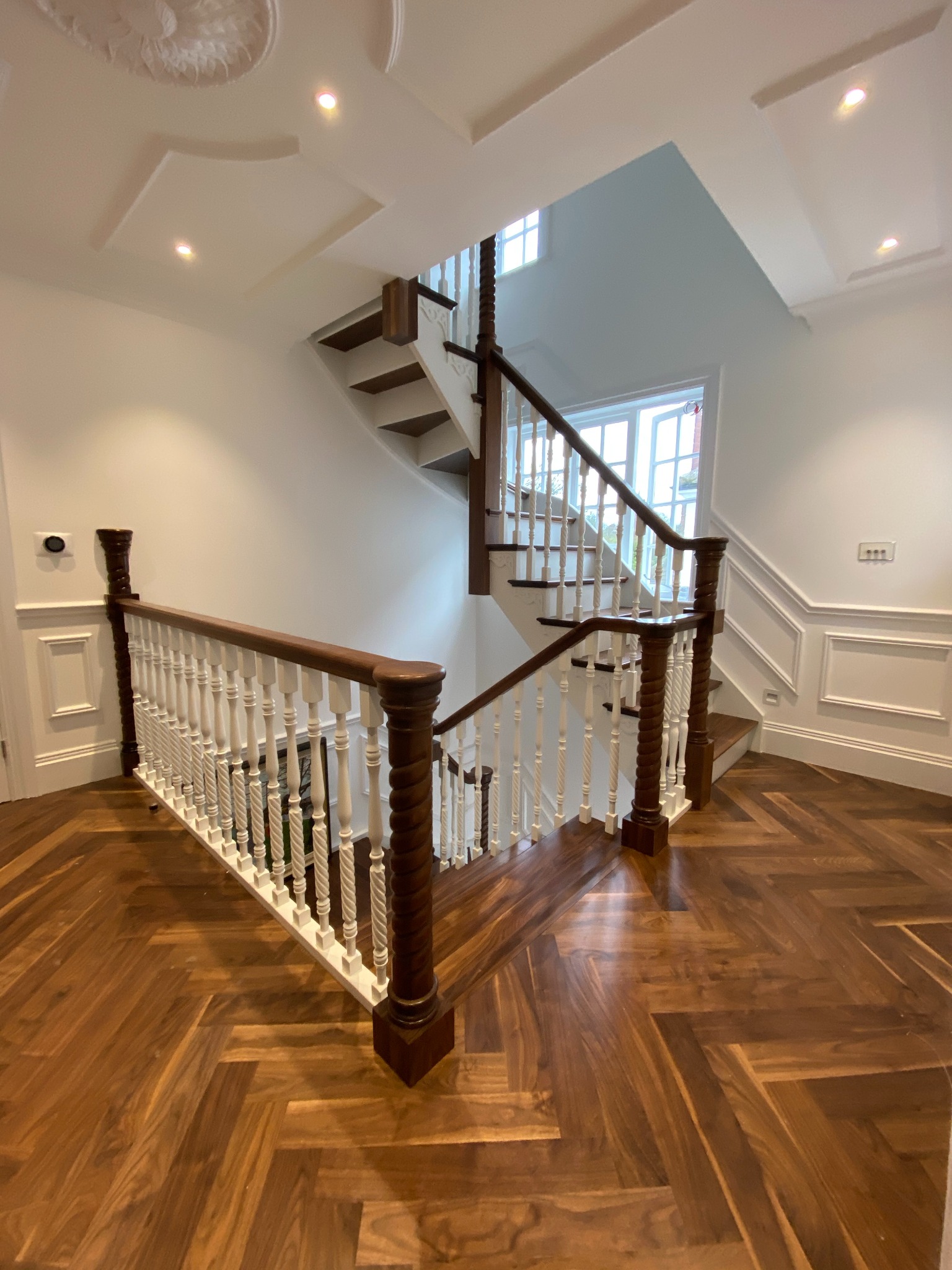 Schody orzechowo brzozowe z balustradą tralkową na słupach z dużą ilością zdobień