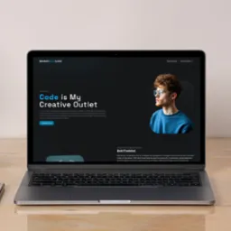 Laptop wyświetlający landing page z portfolio młodego programisty Java, obok smartfon, długopis i słuchawki na drewnianym biurku.