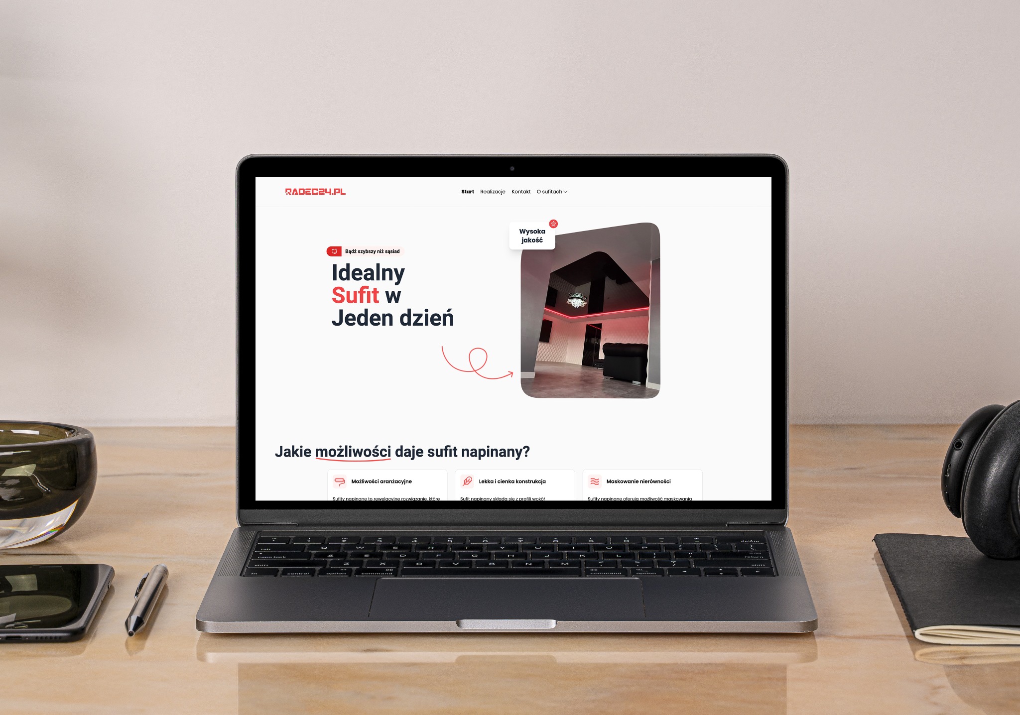 Laptop wyświetla stronę internetową radec24.pl prezentującą ofertę sufitów napinanych. Widoczny fragment strony z hasłem 'Idealny Sufit w Jeden dzień' oraz miniaturą aranżacji wnętrza z sufitem...