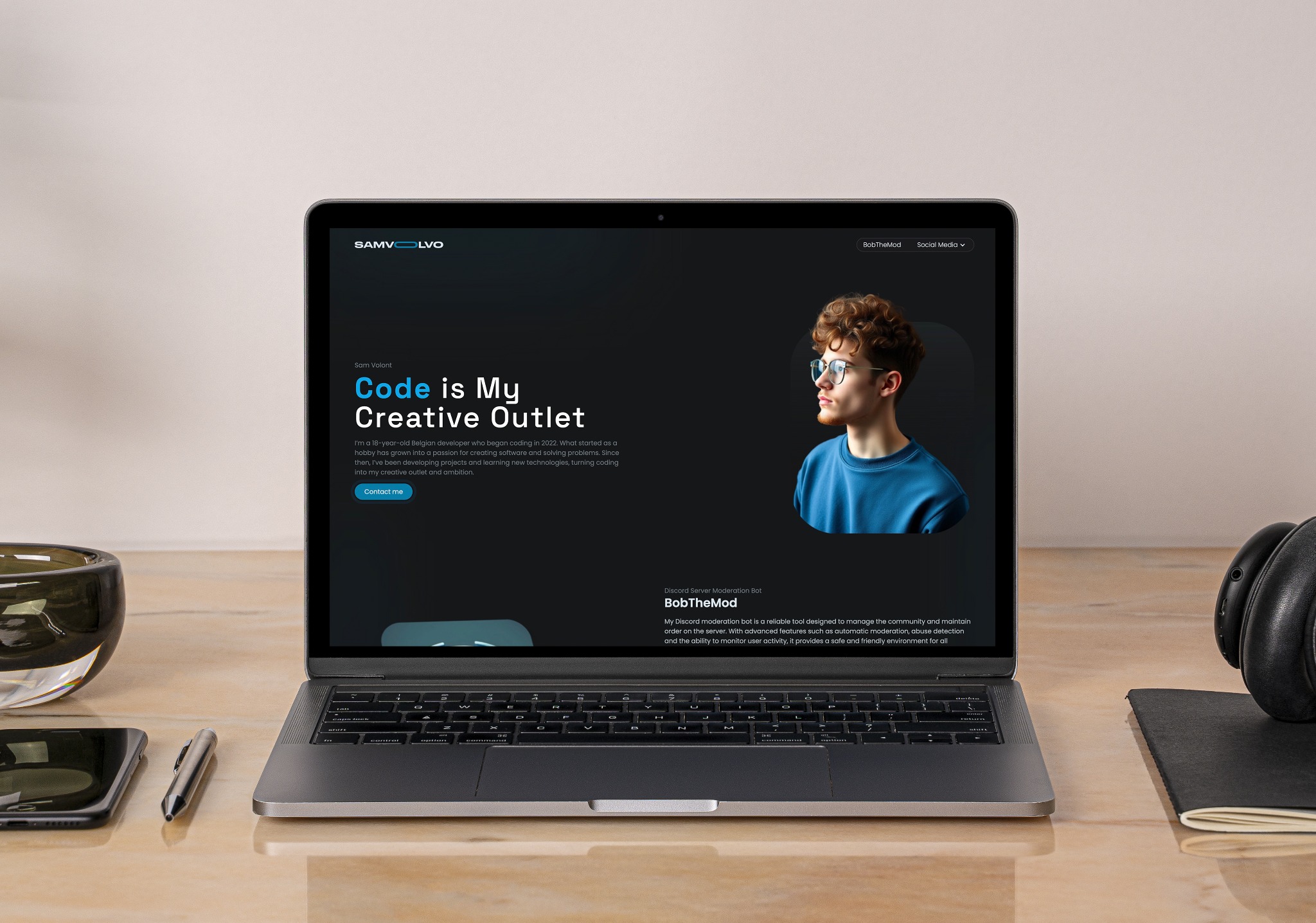 Laptop wyświetlający landing page z portfolio młodego programisty Java, obok smartfon, długopis i słuchawki na drewnianym biurku.