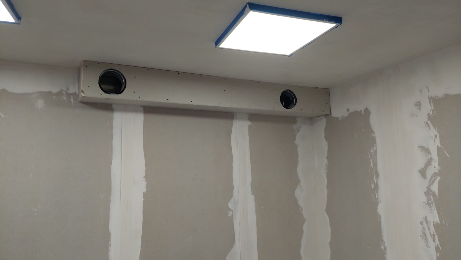 Ściana w trakcie szpachlowania z widoczną instalacją wentylacyjną w zabudowie z płyt gipsowo-kartonowych; widoczne ślady po szpachlowaniu na ścianach.