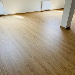 ATS Justyna Grzegorek - Jasne panele podłogowe ułożone w nowym pokoju z grzejnikami i filarem, widok z góry.