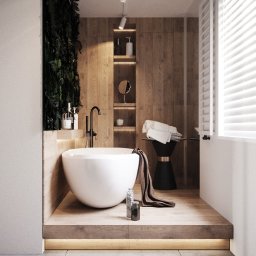 Moye Concept - Nowoczesna łazienka z wolnostojącą białą wanną na drewnianym podeście z podświetleniem LED, drewniane panele na ścianie, pionowy ogród z roślin, czarna armatura i dekoracje.