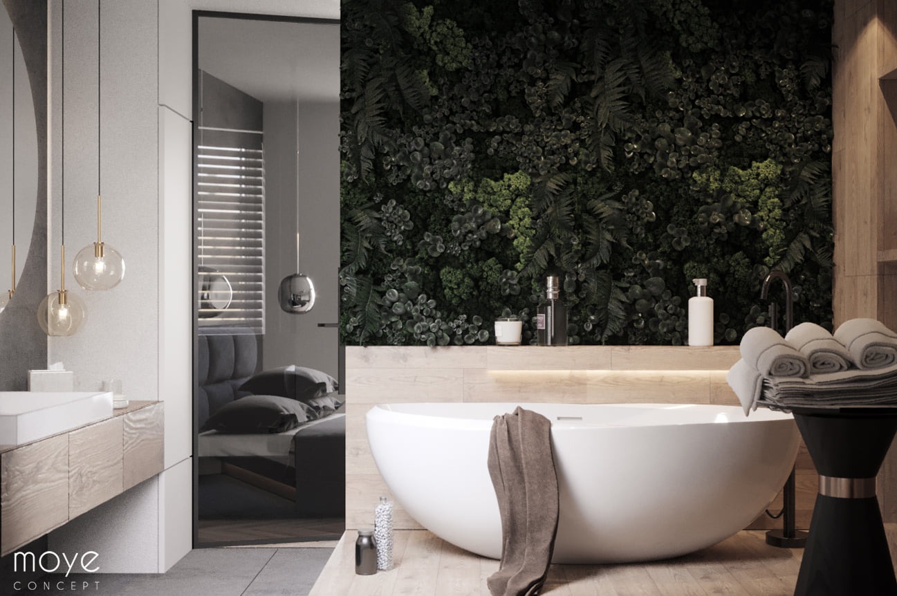 Nowoczesna łazienka z wanną wolnostojącą, ścianą z roślin i widokiem na sypialnię przez szklaną ścianę.