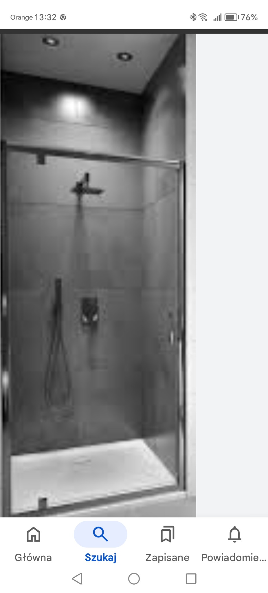 Nowoczesna kabina prysznicowa z szklanymi drzwiami przesuwnymi, chromowanymi elementami i deszczownicą w minimalistycznej łazience w odcieniach szarości.