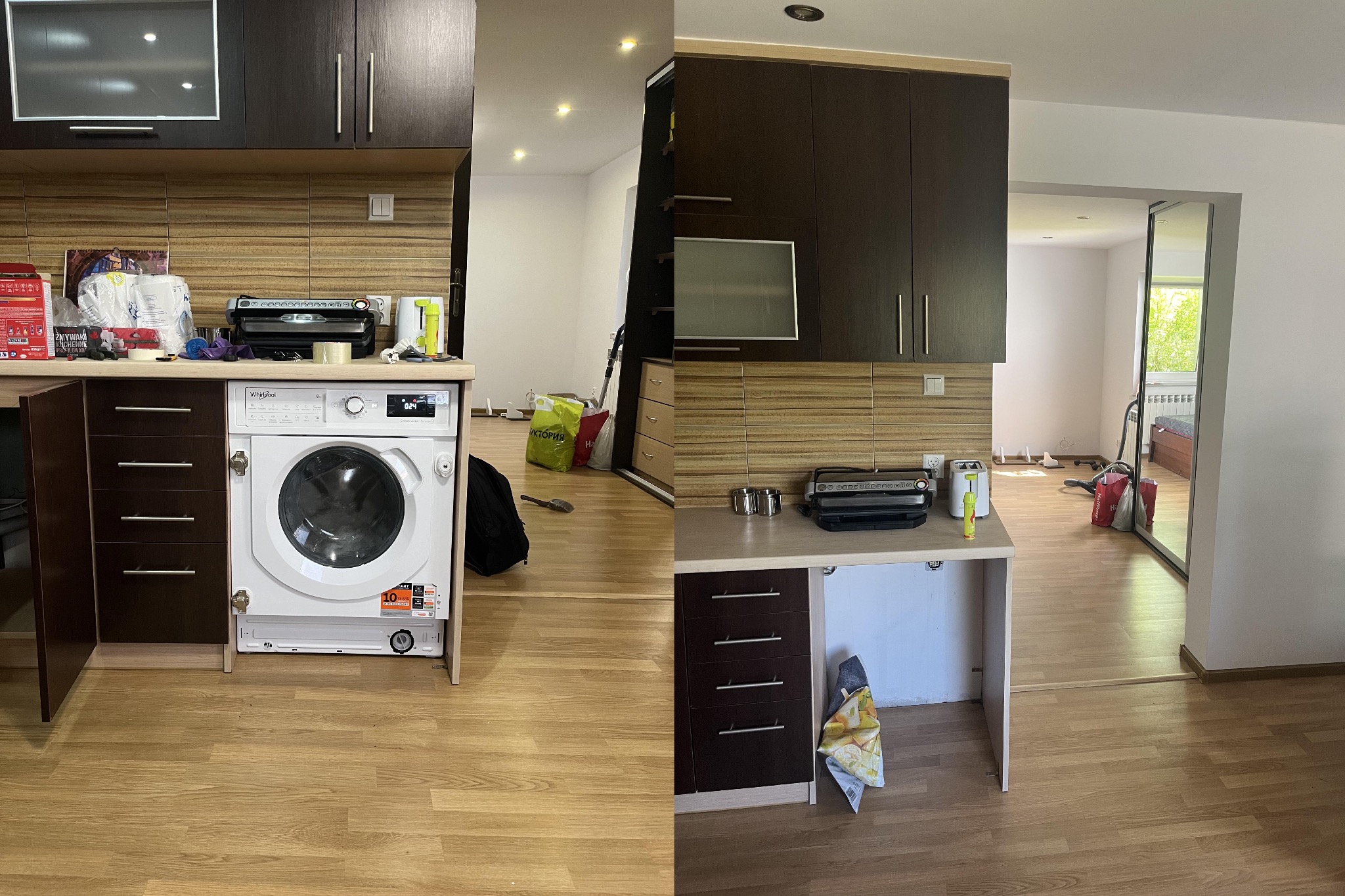 Kuchenna zabudowa z brązowymi szafkami i pralką w zabudowie, widok na otwartą przestrzeń z podłogą panelową i elementami wyposażenia w tle.