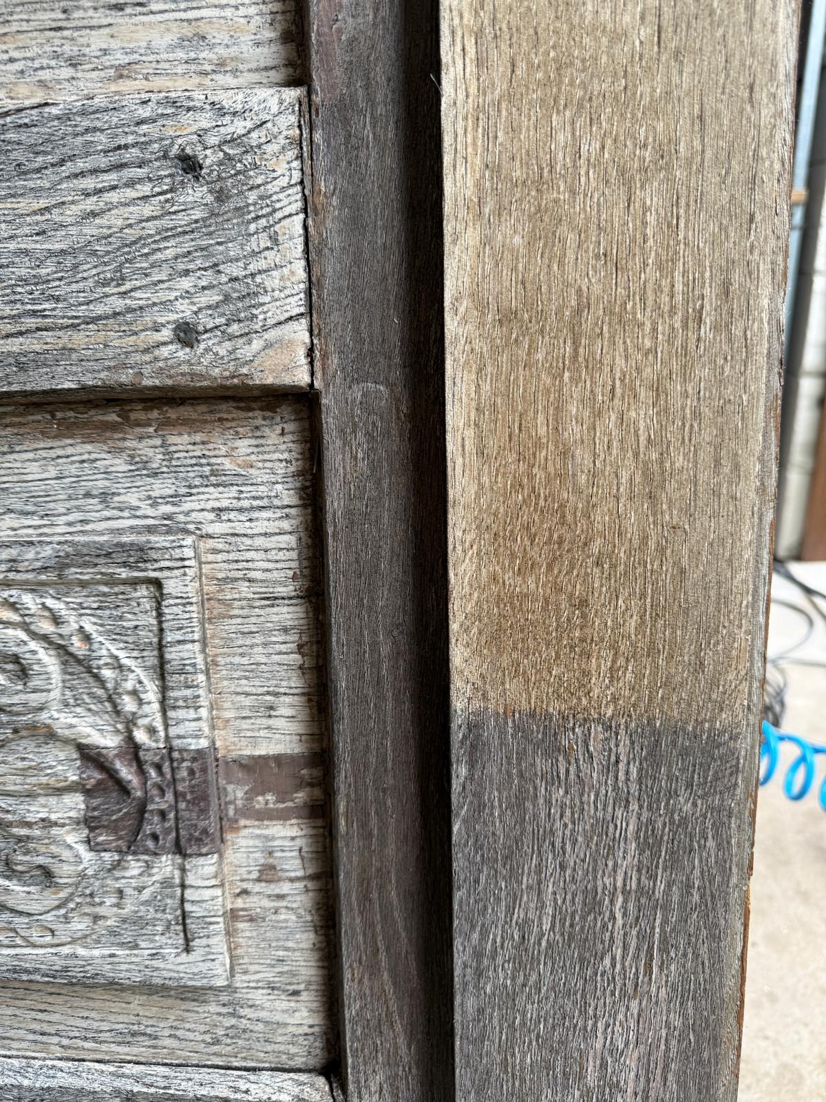 Fragment odrestaurowanych, drewnianych drzwi z dekoracyjnymi elementami i widoczną różnicą w kolorze po czyszczeniu, ukazujący efekt pracy konserwatorskiej.