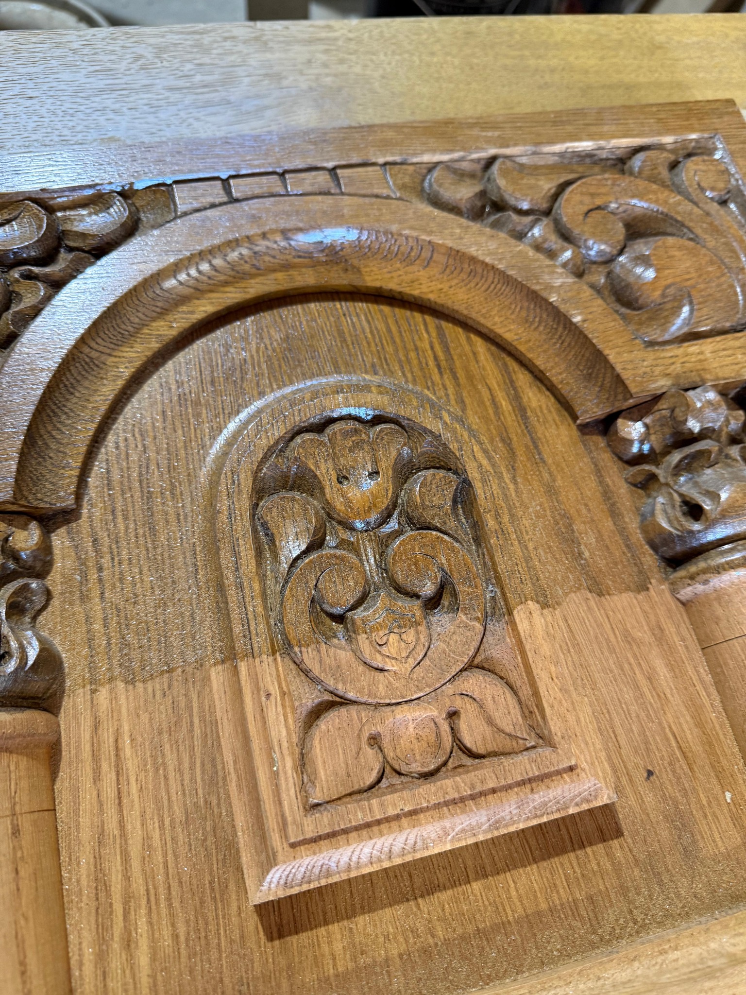 Fragment drewnianej, rzeźbionej dekoracji architektonicznej z motywami roślinnymi. Widoczne detale i tekstura drewna po częściowym oczyszczeniu.