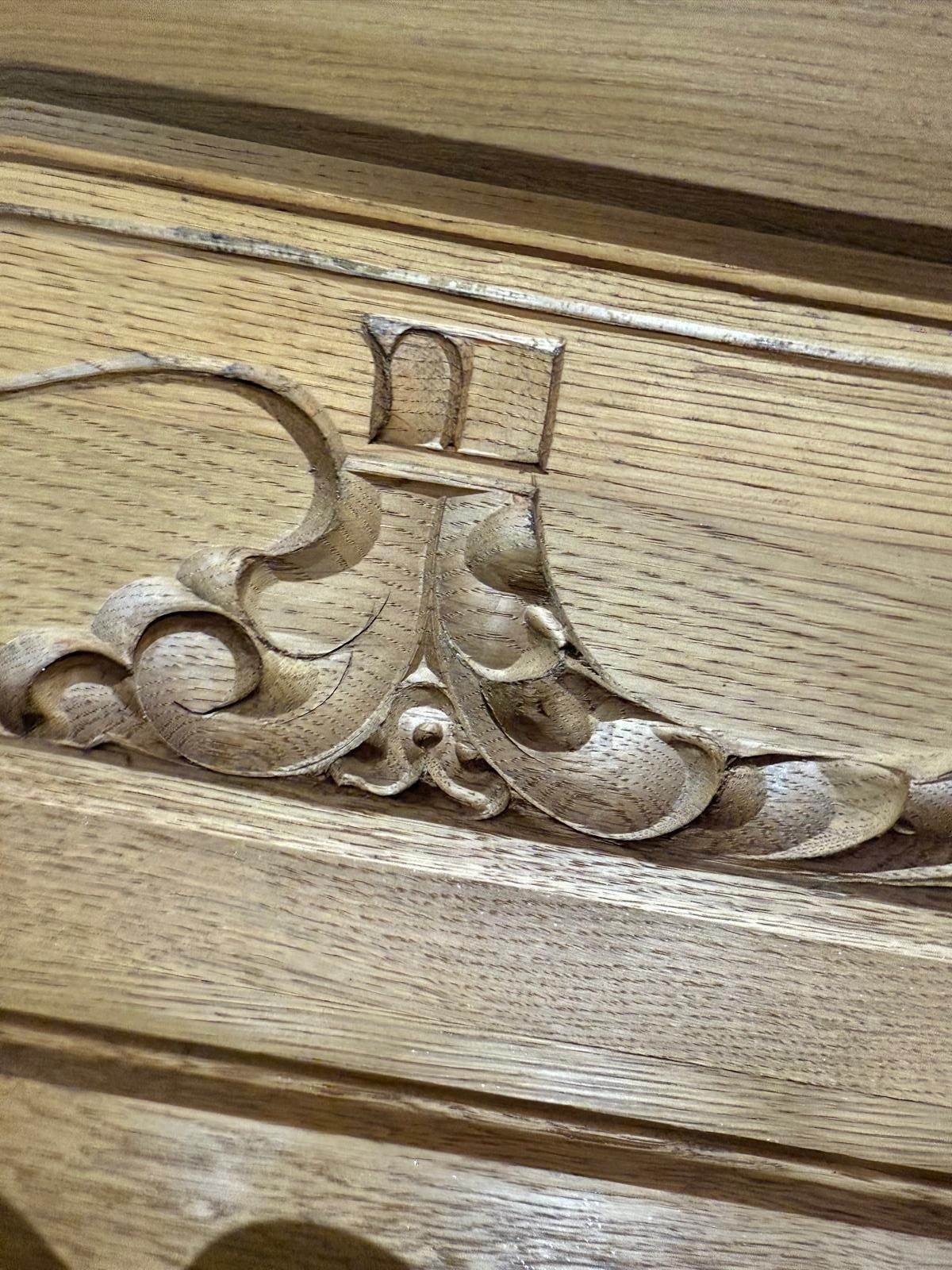 Detal rzeźbionej, drewnianej dekoracji mebla w ciepłym odcieniu brązu, ukazujący precyzyjne wykonanie i unikalny wzór.