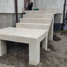 Ruslan Iva - Zewnętrzne schody wejściowe do budynku wyłożone jasnymi płytkami ceramicznymi, z czarnym kotem siedzącym na górnym stopniu