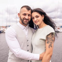 Piotr Wojnarowski - Zakochana para w Szczecinie pozuje na tle przystani jachtowej. Kobieta ma tatuaż na ramieniu, mężczyzna ubrany jest w elegancką kamizelkę.