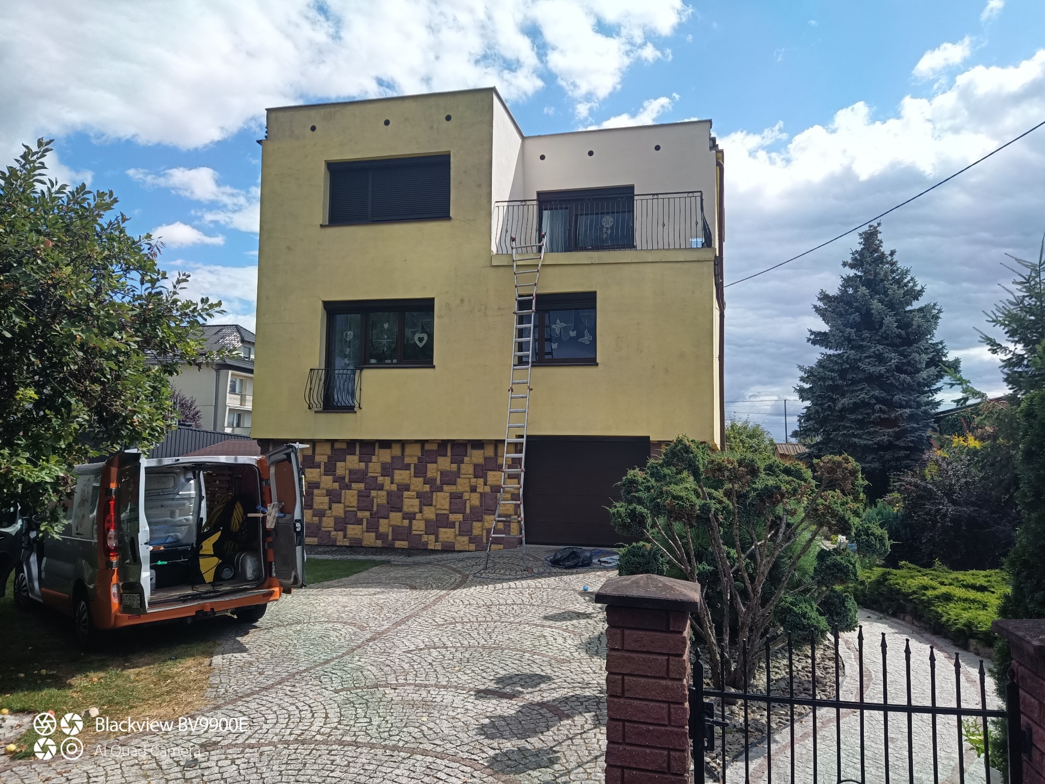 Dwupiętrowy dom z drabina oparty o balkon, częściowo pomalowany na biało. W tle błękitne niebo. Usługi malarskie w Trzciance.