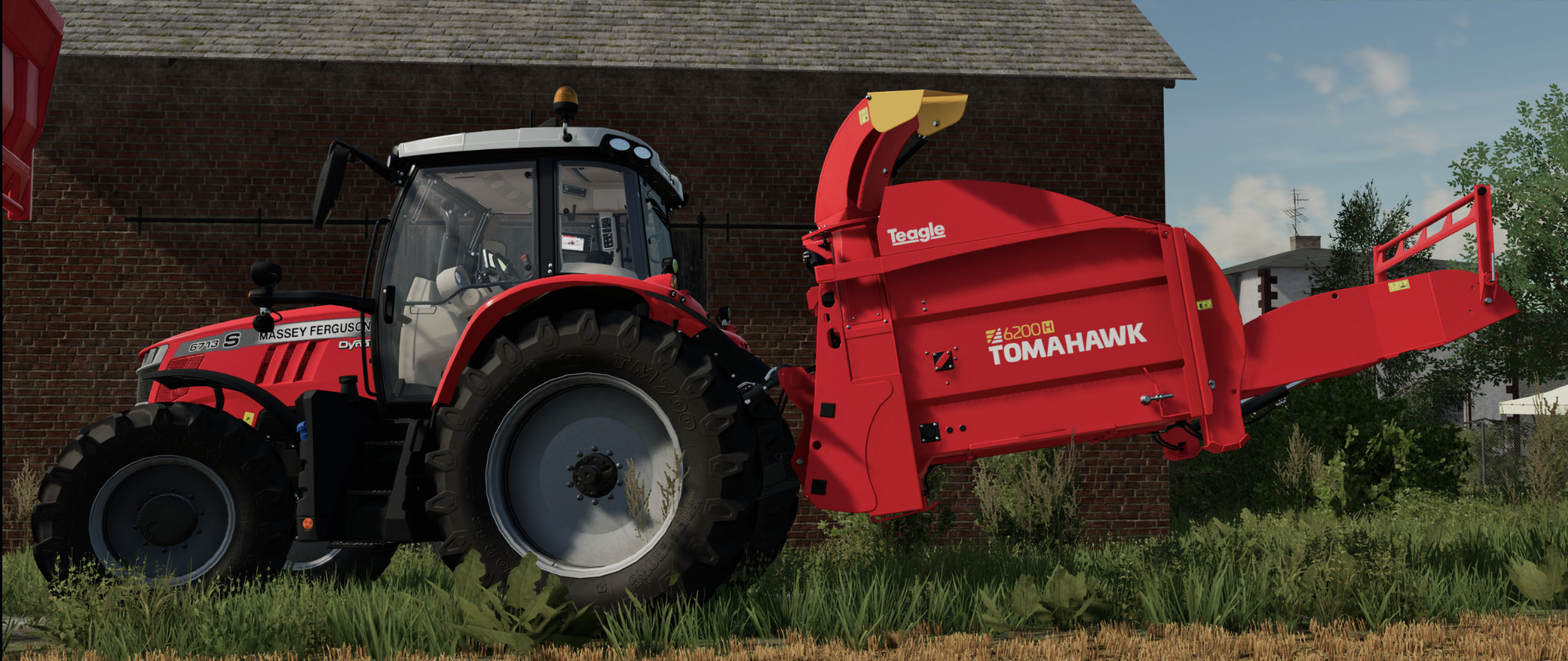 Czerwony traktor Massey Ferguson z zamontowanym rozrzutnikiem obornika Teagle Tomahawk 6200H na tle ceglanego budynku.