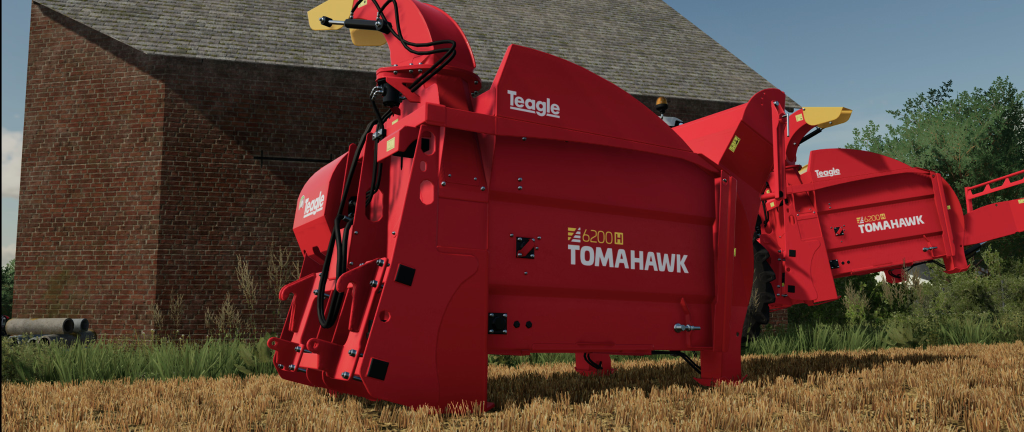 Czerwona maszyna rolnicza Teagle Tomahawk 6200H na polu, z budynkiem gospodarczym w tle.