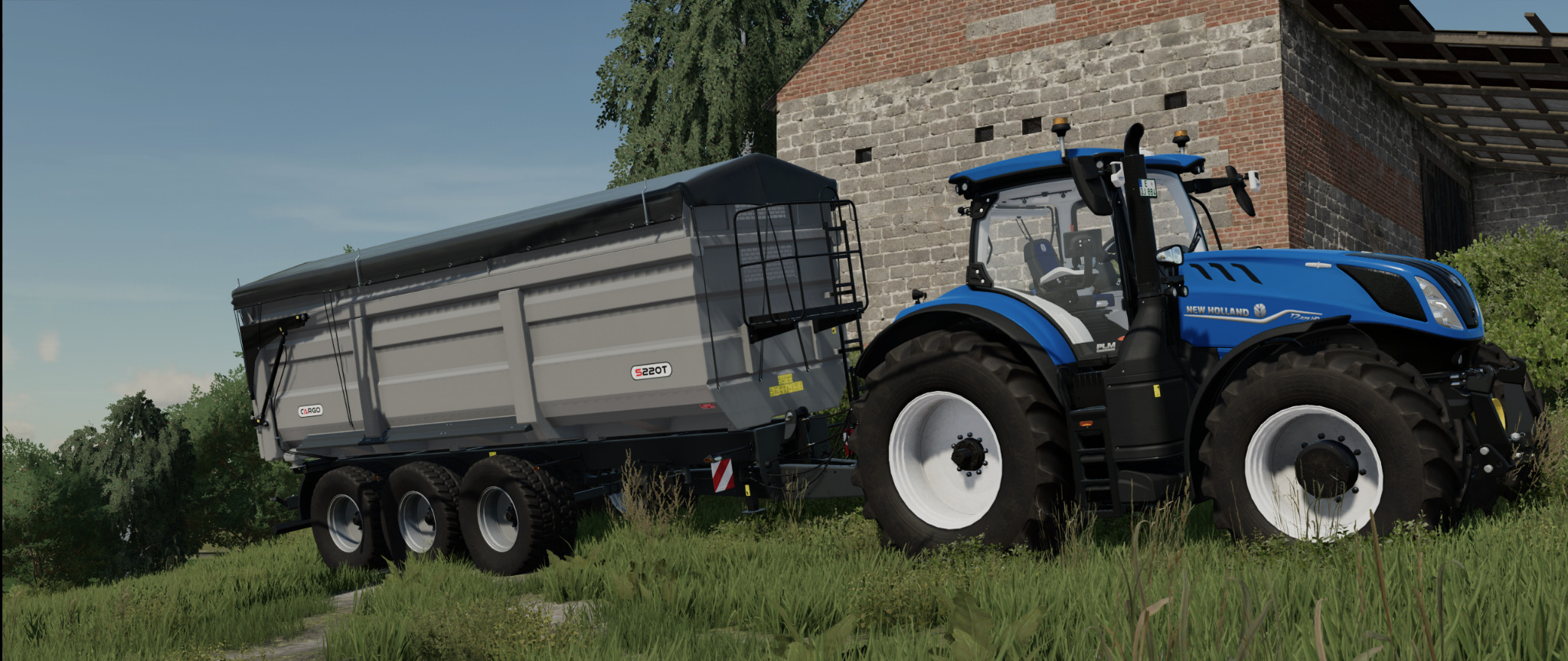 Niebieski ciągnik New Holland z szarą przyczepą na tle ceglanego budynku i zieleni.