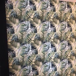 Andrzej Samerdak - Ściana w Piastowie pokryta tapetą z motywem liści palmowych w odcieniach zieleni i błękitu, sąsiadująca z czarną zasłoną i fragmentem jasnoróżowej ściany.