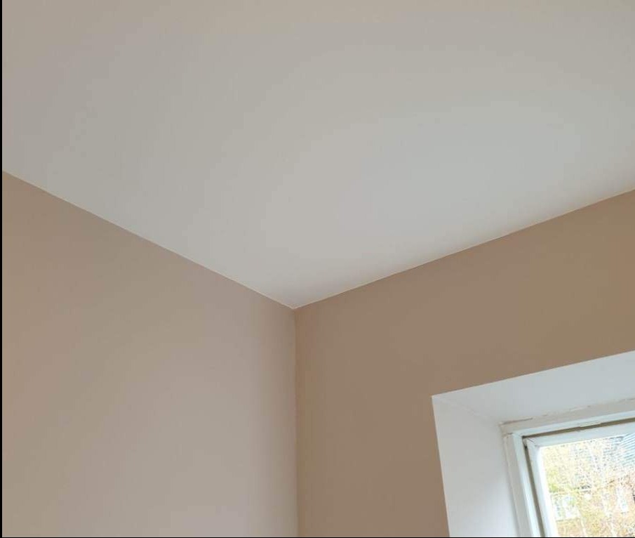 Pomieszczenie po remoncie: Ściany w odcieniach beżu i biały sufit, widoczne okno z białymi ramami.