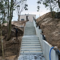 KAMMAR - Schody z kostki brukowej prowadzące na wzgórze, z widoczną pracą ziemną po bokach i zagęszczarką w dolnej części kadru.