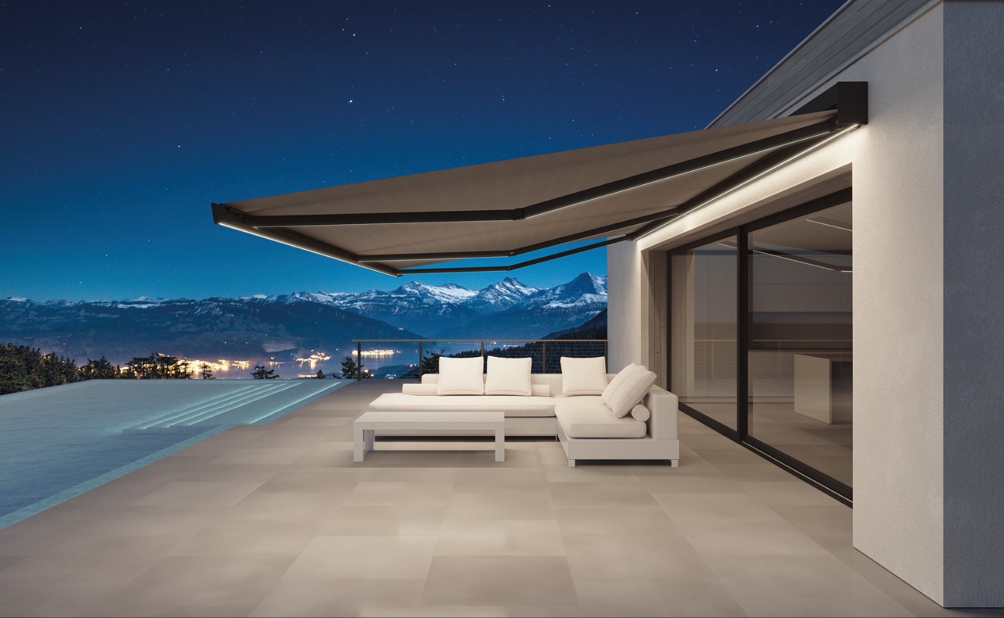 Rozwinięta, podświetlana markiza nad tarasem z białymi meblami wypoczynkowymi, w tle nocny widok na oświetlone miasto i ośnieżone szczyty górskie.