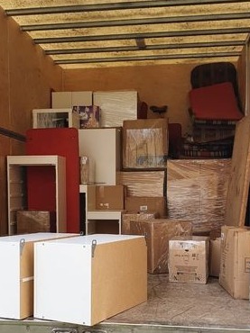 Wnętrze przestrzeni ładunkowej wypełnione meblami i kartonami, przygotowanymi do transportu, zabezpieczonymi folią stretch.