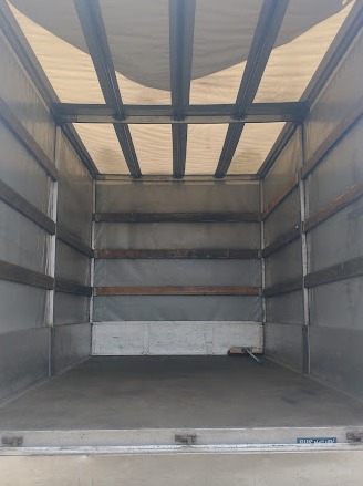 Wnętrze pustej przestrzeni ładunkowej samochodu dostawczego z widocznymi metalowymi wzmocnieniami i drewnianymi listwami ochronnymi na ścianach.