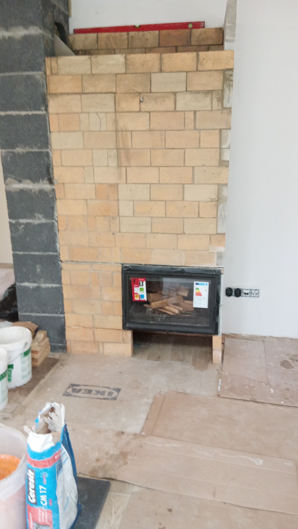 Budowa kominka z cegły w Sochaczewie, widoczne materiały budowlane i wkład kominkowy. Świeżo wymurowana konstrukcja z cegły.