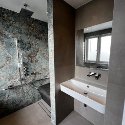 CP Bathrooms Krzysztof Pajor - Nowoczesna łazienka z kabiną prysznicową wyłożoną marmurową mozaiką w odcieniach błękitu i brązu, chromowaną armaturą i siedziskiem z czarnej mozaiki, oraz białą, prostokątną umywalką zamontowaną...
