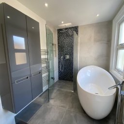 CP Bathrooms Krzysztof Pajor - Nowoczesna łazienka z wolnostojącą wanną, kabiną prysznicową z mozaiką, szarą zabudową meblową na wysoki połysk i grzejnikiem drabinkowym