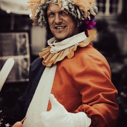 Fomin-Art - Uśmiechnięty mężczyzna w kostiumie klauna z kolorową peruką i balonami modelowanymi, kciuk w górę.