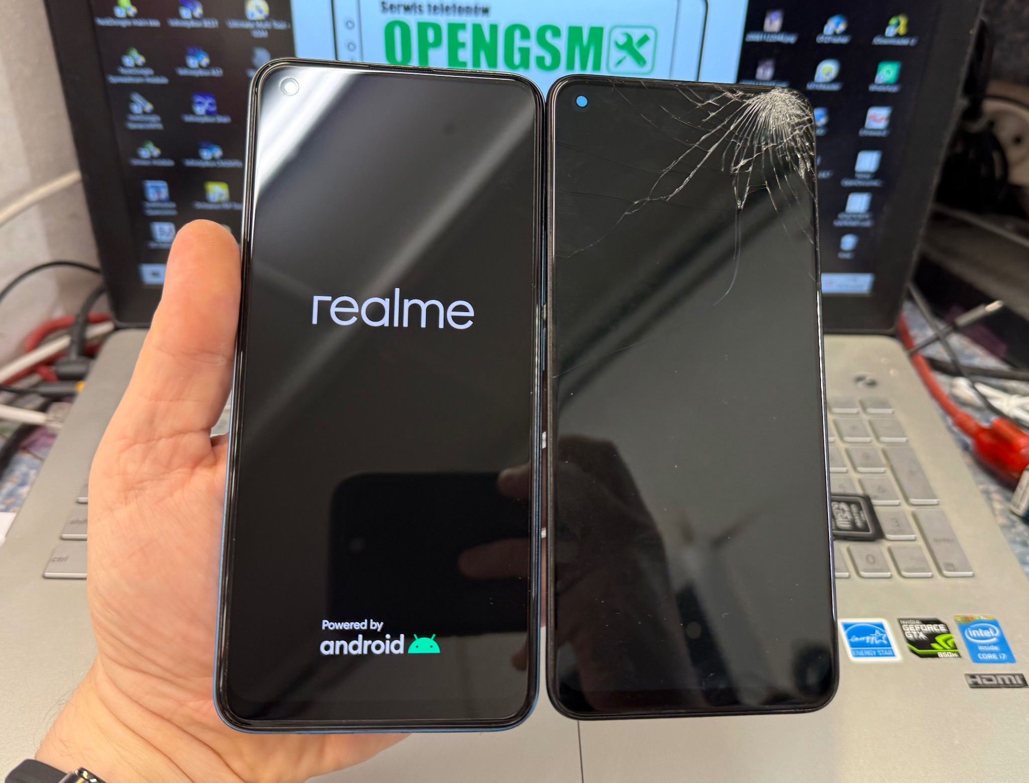 Dwa telefony: sprawny z logo Realme i Android oraz pęknięty, leżące na laptopie z widocznymi naklejkami Intel i Nvidia.
