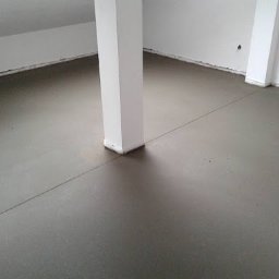 DoMix - Świeżo wylana, gładka posadzka w jasnym pomieszczeniu z filarem nośnym. Widoczna dylatacja w posadzce.