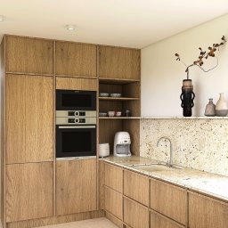 Pracownia Przedpokój Joanna Gołos - Jasna kuchnia z drewnianymi szafkami, wbudowanym piekarnikiem i mikrofalówką Bosch. Na blacie granitowym ekspres do kawy i toster Smeg.