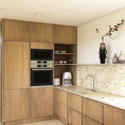 Jasna kuchnia z drewnianymi szafkami, wbudowanym piekarnikiem i mikrofalówką Bosch. Na blacie granitowym ekspres do kawy i toster Smeg.