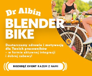 Żółty baner reklamowy z rowerem-blenderem, hasłem 'Blender Bike' i tekstem o dostarczaniu zdrowia i motywacji pracownikom. Piknik firmowy w tle, aktywna integracja.