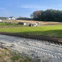 Niwelacja całego terenu wraz z wykonaniem nasypu  pod drogę. Wykonanie drogi w stabilizacji gruntu cementem, wykończenie kruszywem frakcja 4/32 