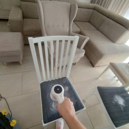 Przedsiębiorstwo Usługowe Paulina Gliszczyńska - Czyszczenie tapicerki krzesła za pomocą elektrycznej szczotki do usuwania sierści i zmechaceń, widoczny efekt zbierania zabrudzeń, w tle narożnik, fotel i pufa w odcieniach beżu.