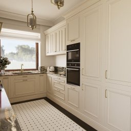 Maya Design - Jasna kuchnia w stylu klasycznym z marmurowym blatem, białymi szafkami i czarnym piekarnikiem oraz ozdobnym telefonem na ścianie.