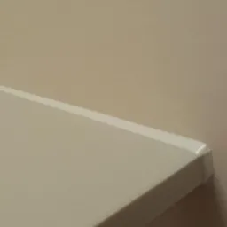 Fragment blatu łazienkowego z idealnie wykonanym silikonowaniem przy ścianie, prezentujący precyzję wykończenia detali. Stonowana kolorystyka wnętrza.