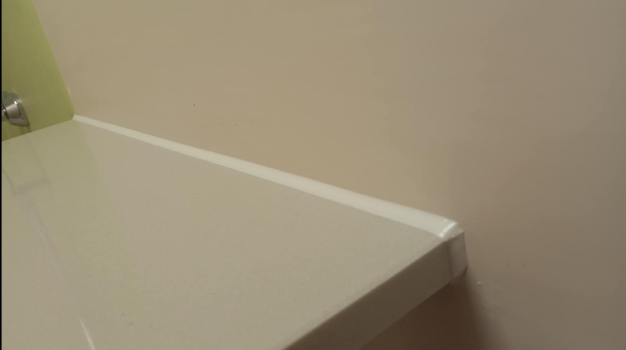 Fragment blatu łazienkowego z idealnie wykonanym silikonowaniem przy ścianie, prezentujący precyzję wykończenia detali. Stonowana kolorystyka wnętrza.