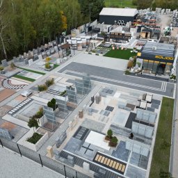 Solido - centrum architektury krajobrazu - Ekspozycja zewnętrzna kostki brukowej i elementów betonowych, widok z góry, prezentująca różnorodność wzorów i kolorów, otoczona zielenią drzew i krzewów.