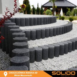 Solido - centrum architektury krajobrazu - Kaskadowe schody ogrodowe z szarej kostki granitowej, obrzeża z ciemnych, okrągłych słupków, widok z boku, w tle altana ogrodowa.