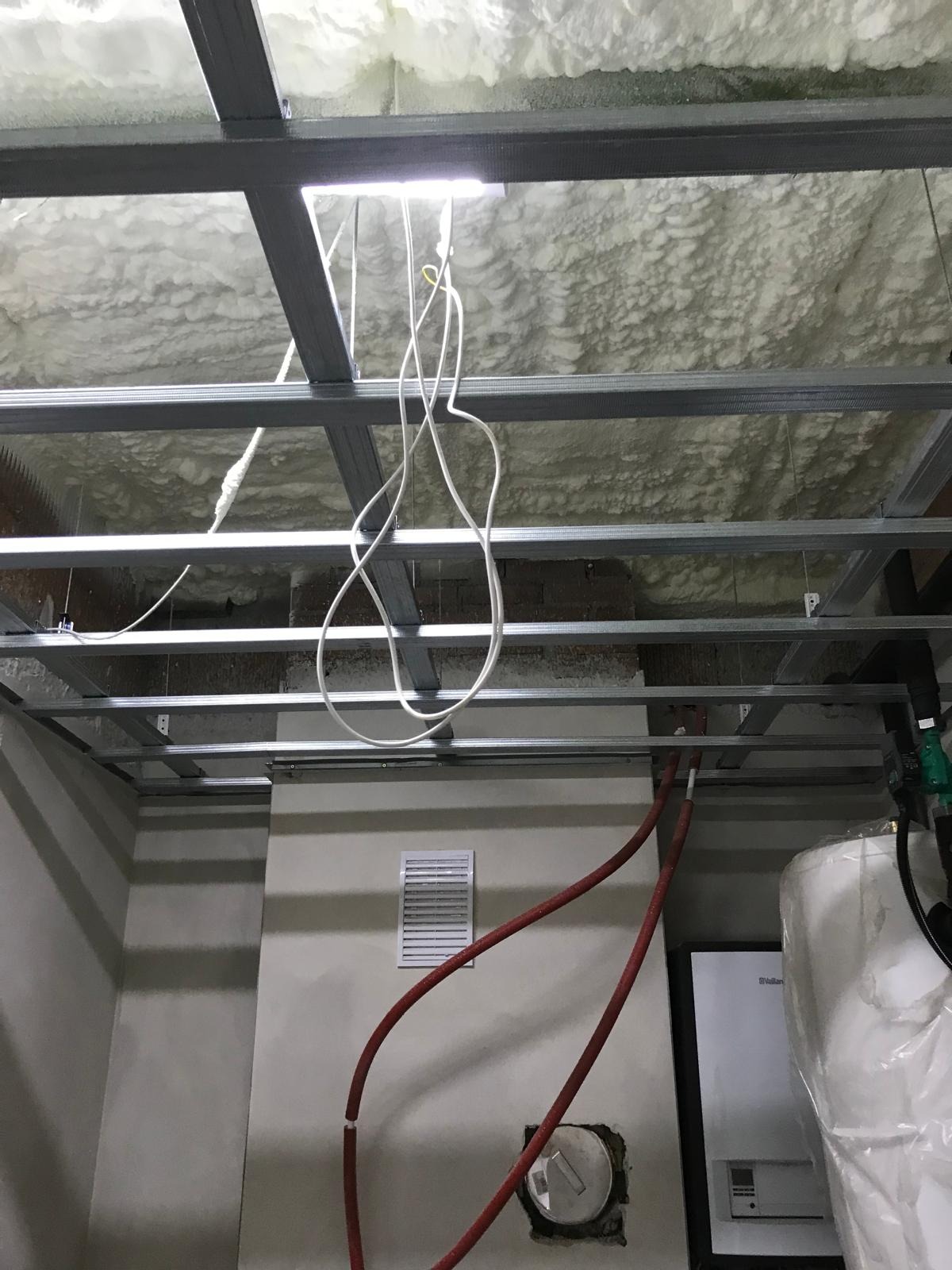 Montaż sufitu podwieszanego z izolacją piankową w Kuźnicy, widoczne profile metalowe i instalacje.