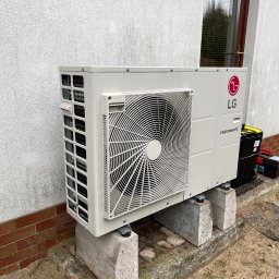 Edison Energy - Zewnętrzna jednostka pompy ciepła LG Therma V, zamontowana na betonowych wspornikach przy ścianie budynku, obok skrzynka z narzędziami.