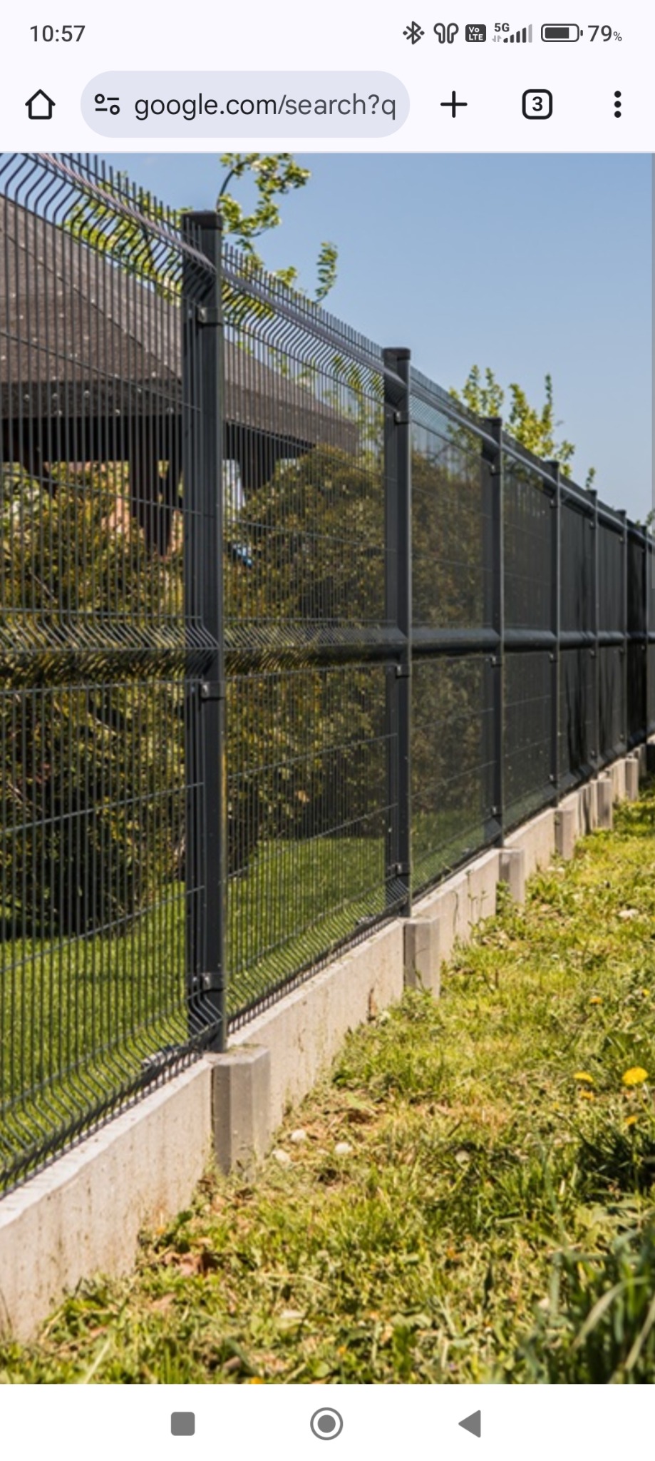 Długi, grafitowy system ogradzający z paneli zgrzewanych, osadzony na betonowej podmurówce z betonowymi słupkami, widok z zewnątrz posesji, w tle zieleń drzew i altana.