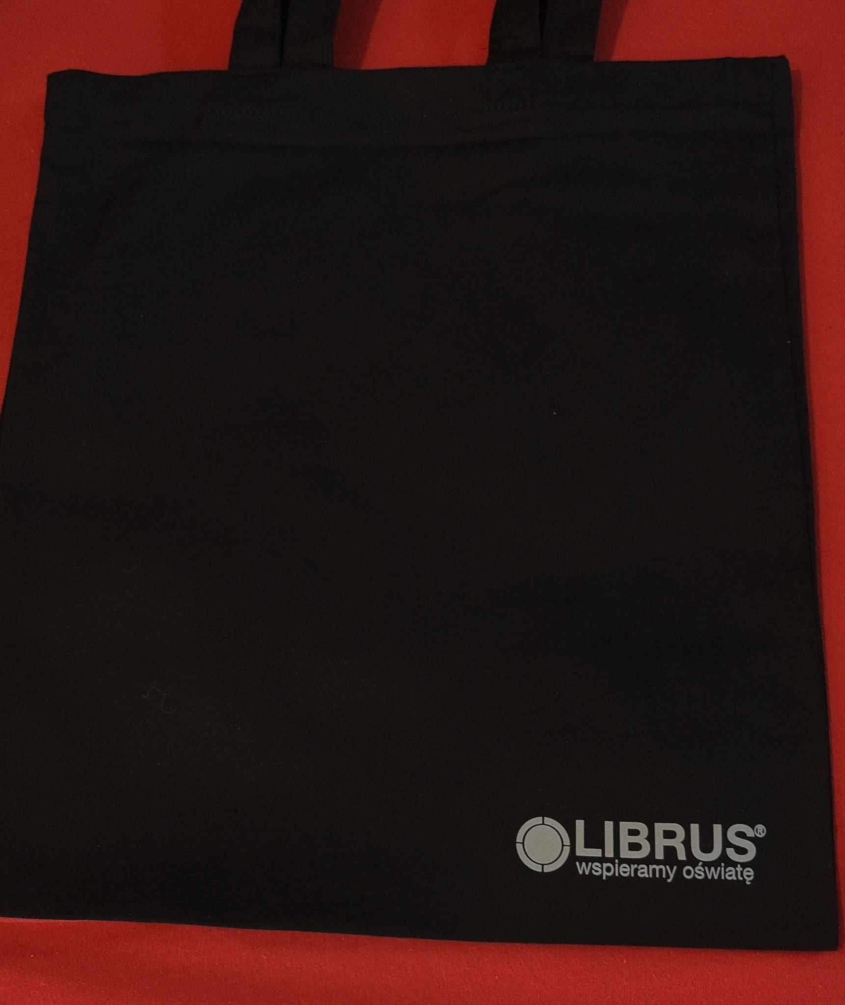 Czarna torba bawełniana z nadrukowanym logo firmy Librus na czerwonym tle.