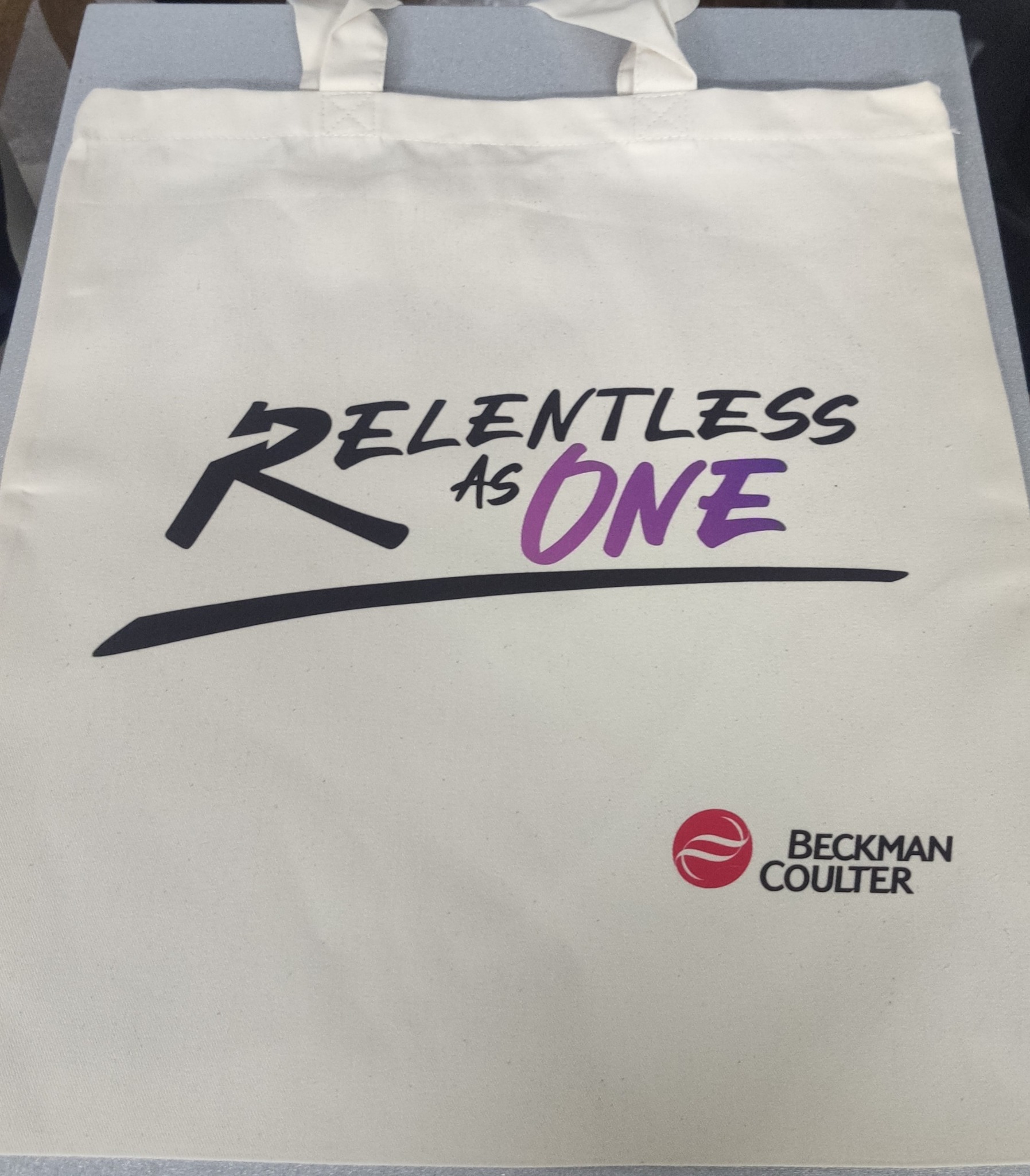 Torba bawełniana z nadrukiem hasła 'Relentless as One' oraz logo firmy Beckman Coulter.
