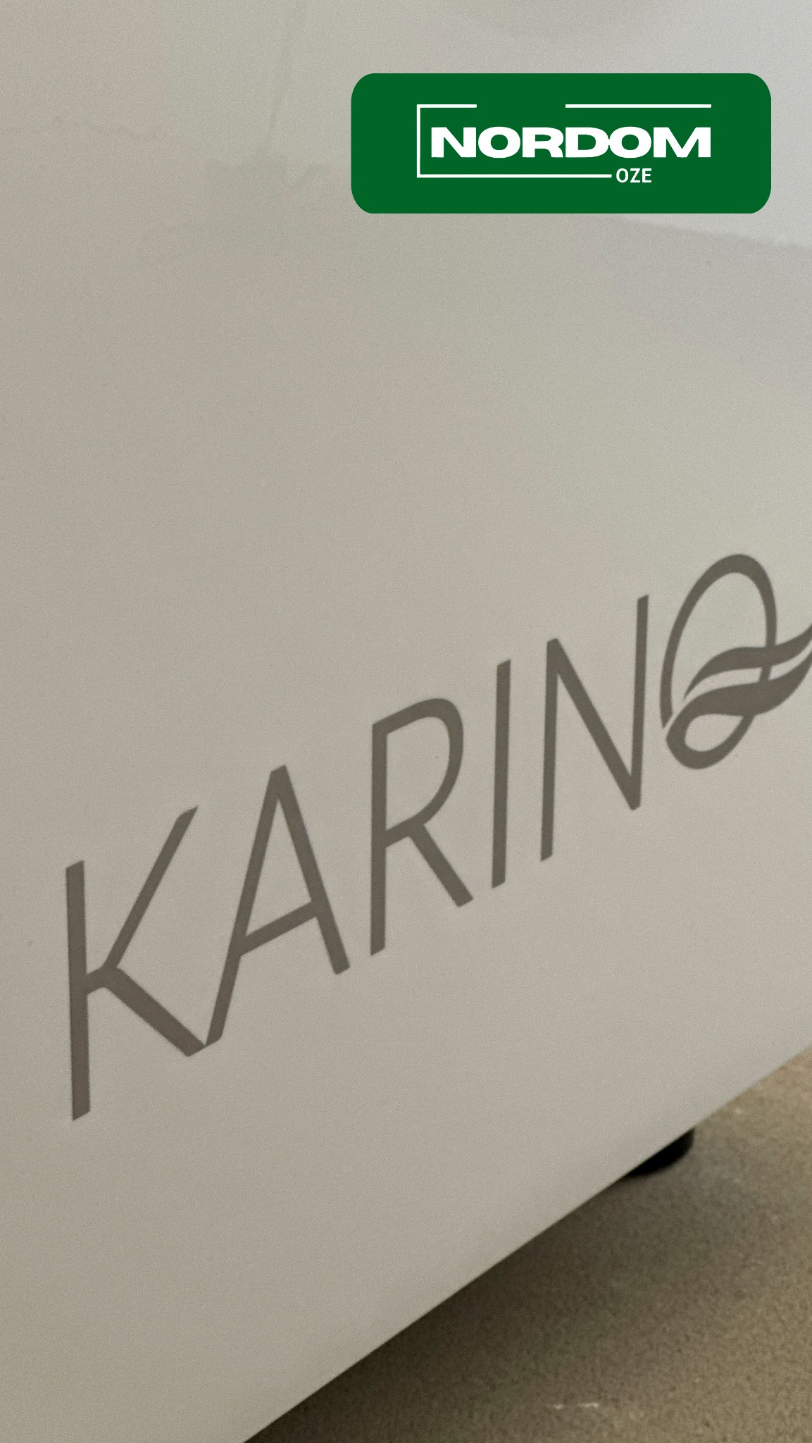 Biała obudowa urządzenia z szarym napisem 'KARINA' i zielonym logo Nordom-OZE w górnym rogu.